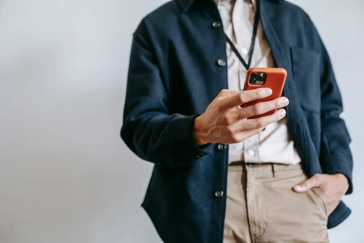 Professional man actively using bright orange smartphone in casual attire.