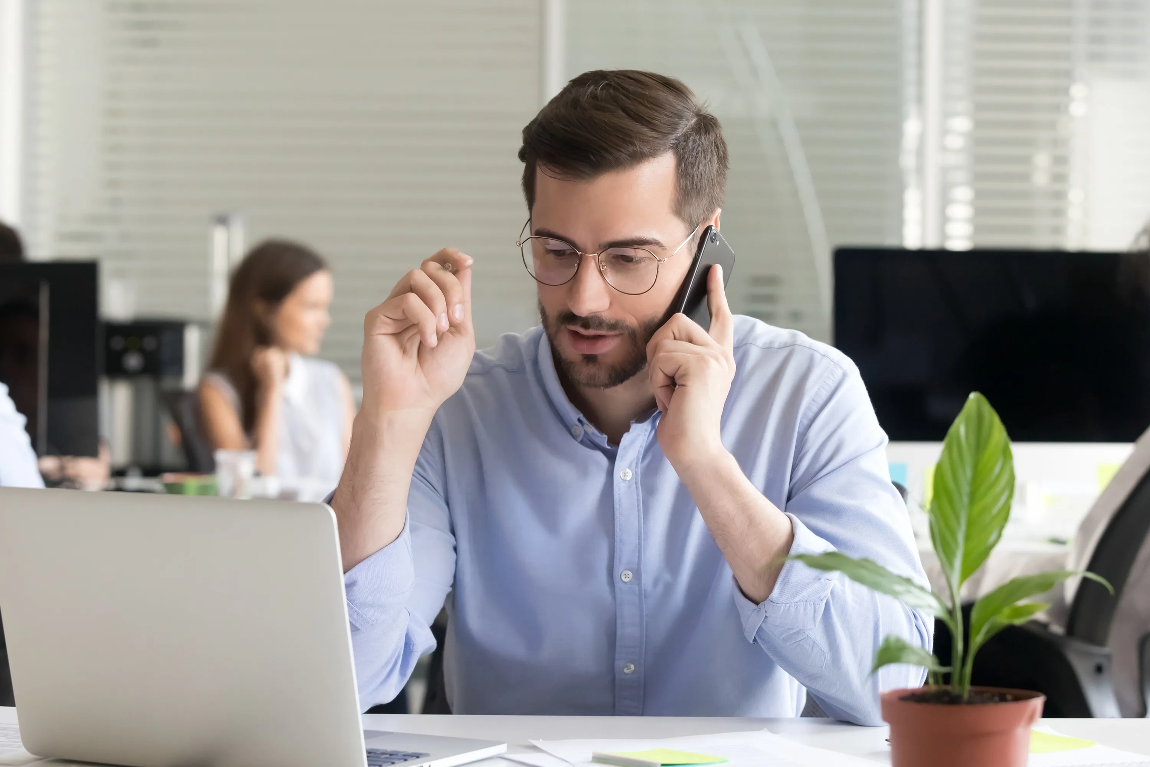 Businessman talking on phone at office desk with laptop.